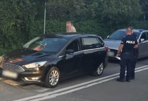 Widziany z góry policjant obok mężczyzny stojącego przy czarnym samochodzie kombi
