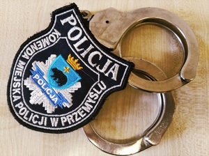 kajdanki policyjne i naszywka koloru czarnego z białym napisem Policja, Komenda Miejska Policji w Przemyślu