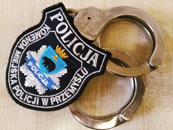 kajdanki policyjne i naszywka koloru czarnego z białym napisem Policja, Komenda Miejska Policji w Przemyślu