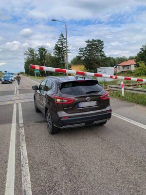 samochód osobowy marki Nissan stoi na przejeździe kolejowym, na ten samochód opuszczony został szlaban