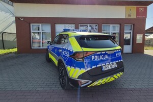 oznakowany radiowóz stoi zaparkowany przed sklepem spożywczym