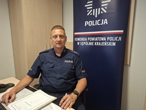 umundurowany policjant siedzi za biurkiem