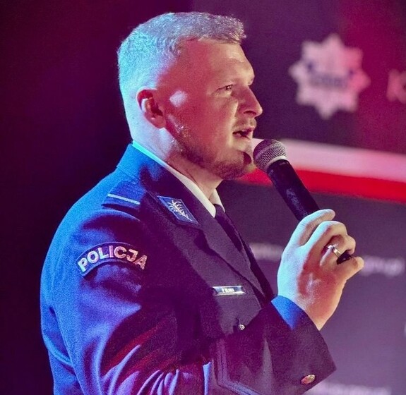 umundurowany policjant śpiewa do trzymanego w ręku mikrofonu