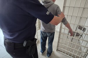 Policjant wprowadza zatrzymanego do celi