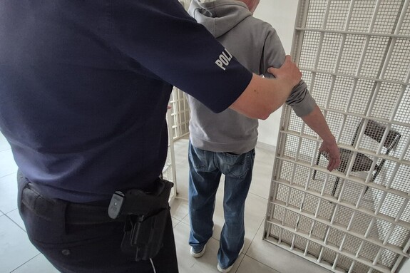 Policjant wprowadza zatrzymanego do celi