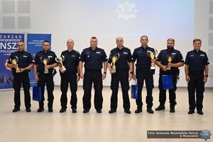W sali ustawieni w rzędzie 8 policjantów z pucharami