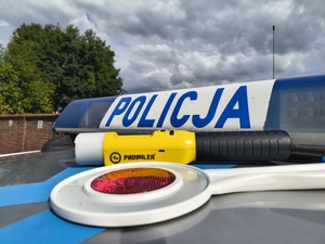 na dachu oznakowanego radiowozu leży tarcza do zatrzymywania pojazdów i urządzenie służące do pomiaru alkoholu w wydychanym powietrzu.