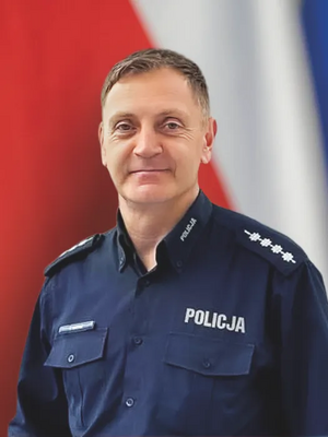 Uśmiechnięty policjant na tle flagi narodowej