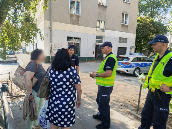 Dwaj policjanci w przestrzeni osiedla rozmawiający z kobietami