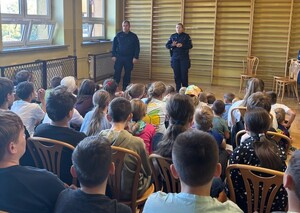 Dwójka policjantów podczas prelekcji dla młodzieży zgromadzonej w sali gimnastycznej
