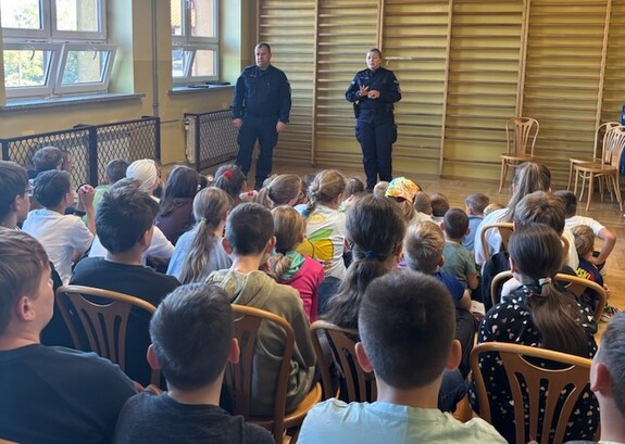Dwójka policjantów podczas prelekcji dla młodzieży zgromadzonej w sali gimnastycznej