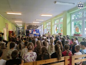 Policjant podczas pogadanki dla dzieci w auli szkolnej