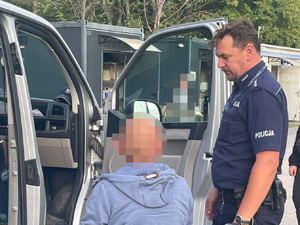 W otwartych drzwiach radiowozu typu bus mężczyzna oraz policjant