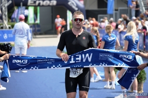 Mężczyzna w stroju sportowym zrywający szarfę linii mety