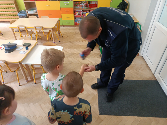 P:ochylicjant pochylający się nad dziećmi w sali przedszkolnej