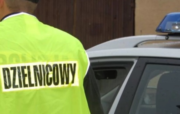 Plecy policjanta w kamizelce odblaskowej z napisem dzielnicowi