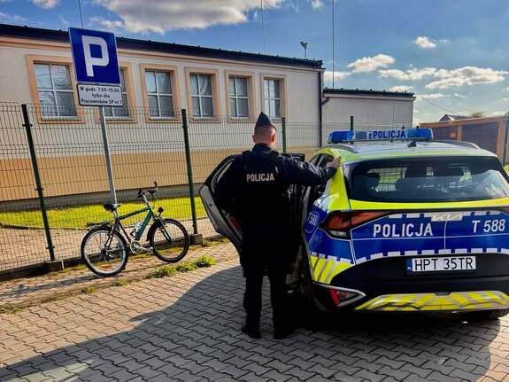 Policjant obok radiowozu na parkingu