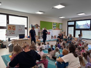 Pogadanka dwójki policjantów dla dzieci w sali szkolnej