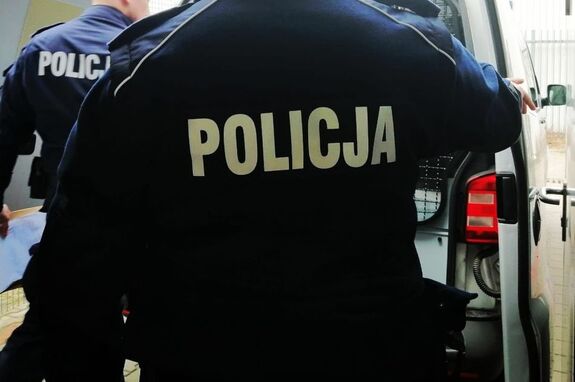 Plecy policjanta na tle radiowozu typu van