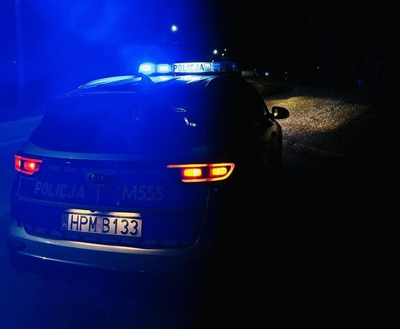 Radiowóz z włączonymi lampami błyskowymi w scenerii nocnej