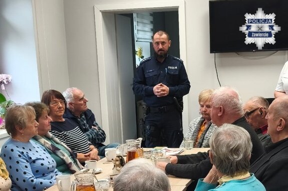 Policjant podczas prelekcji dla zgromadzonych przy stole konferencyjnym
