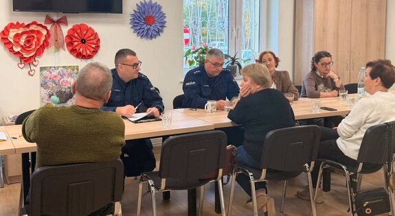 Dwóch umundurowanych policjantów na spotkaniu z seniorami
