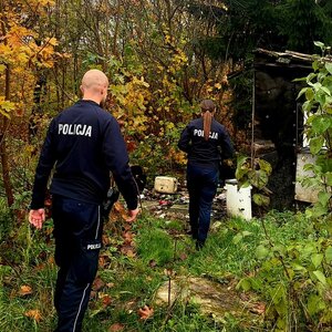 Zdjęcie przedstawiające dwoje policjantów podczas kontroli miejsca przebywania osoby bezdomnej w altanie działkowej.